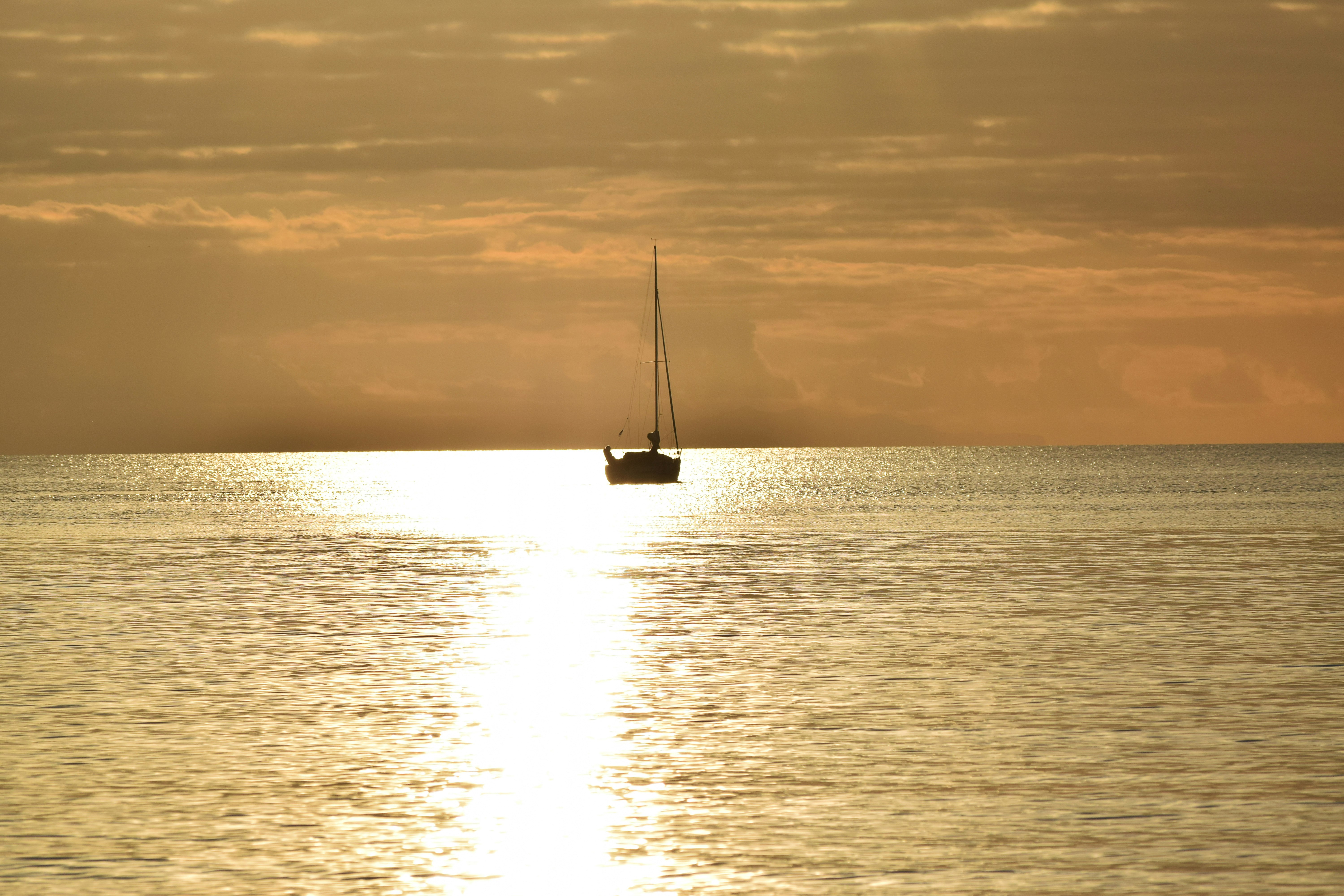 white sailboat on sea under gray sky